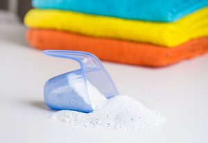 a scoop of washing powder in front of a pile of folded towels